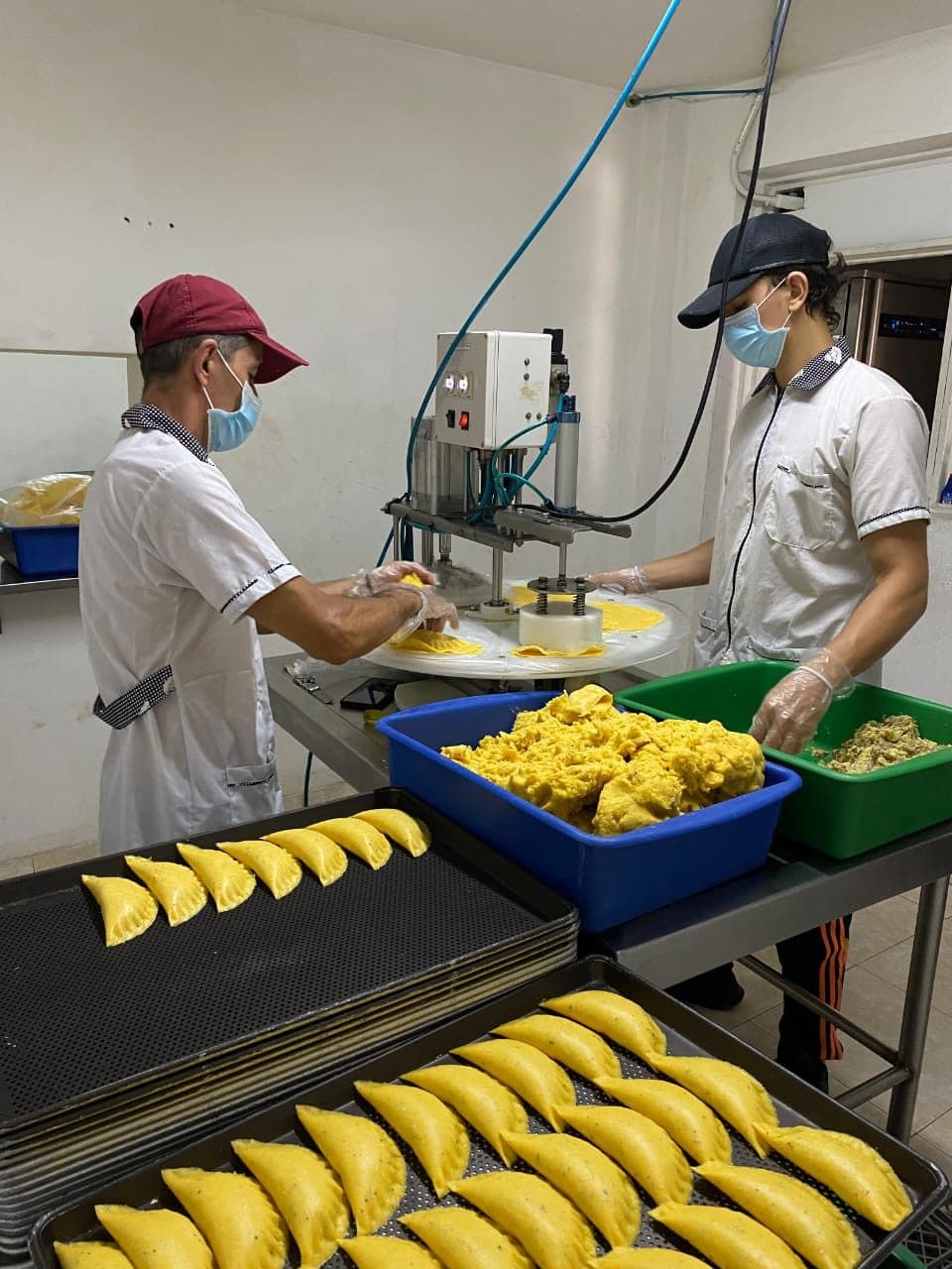 Equipo de Croky armando empanadas en la máquina formadora de la fábrica